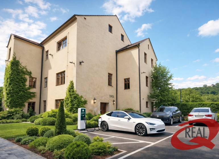 Épület Nagyugrócban zöldterülettel és elektromos autók töltőállomásával a parkolóban.