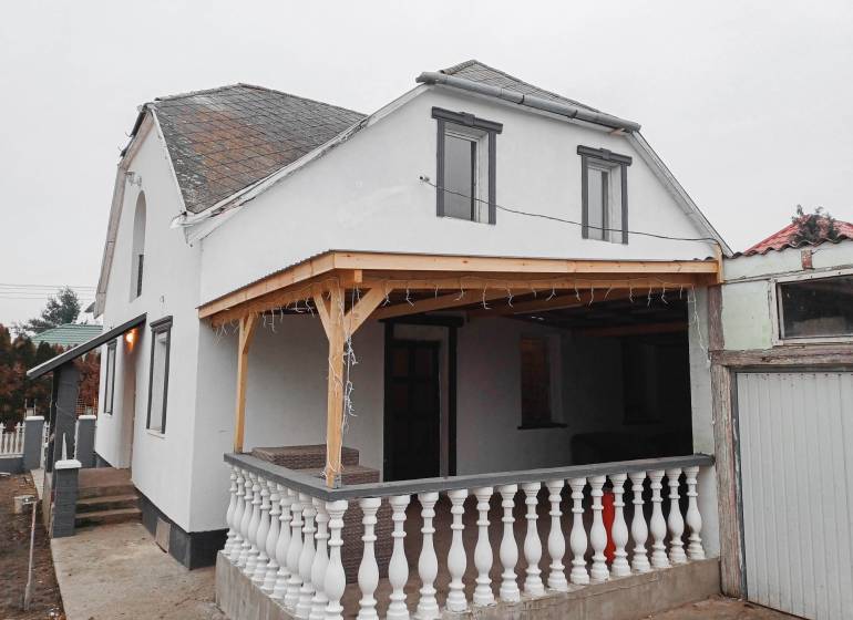 Vizsolyi családi ház terasszal, fehér homlokzattal és fa előtetővel.