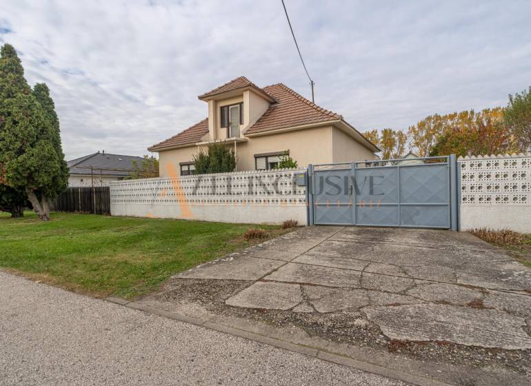 Családi ház Nagydobronyban nagy kerttel, fákkal és beton járdával.