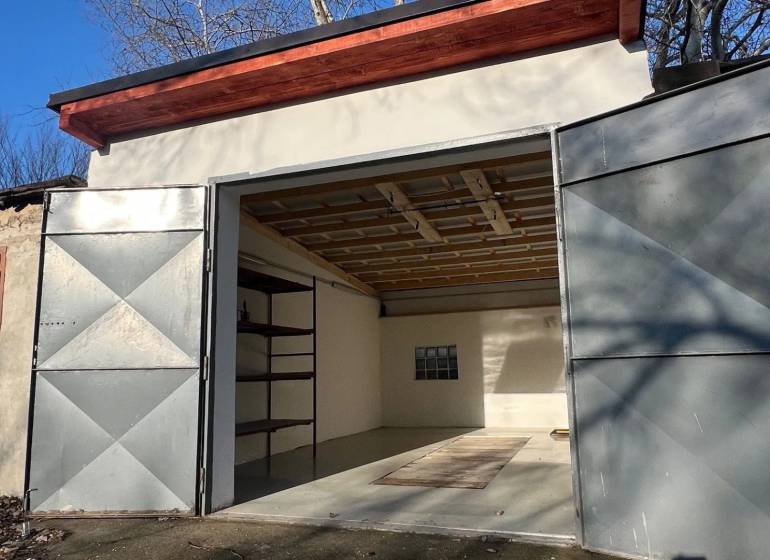 Nyitott garázs az Agátová utcában, Pozsony-Dúbravkán, egyszerű belső térrel és polccal.