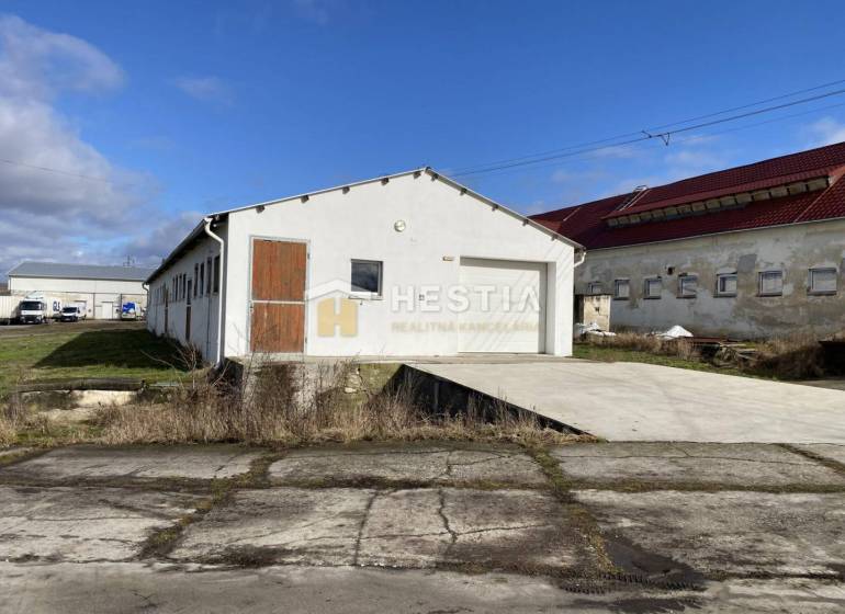 Raktárak és csarnokok külső része Rybkyben fehér homlokzattal és faajtókkal.