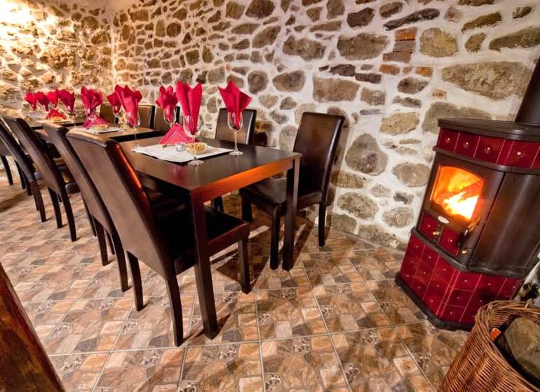 Rusztikus gasztronómiai terek kandallóval, kőfallal és asztalokkal, szalvétákkal.