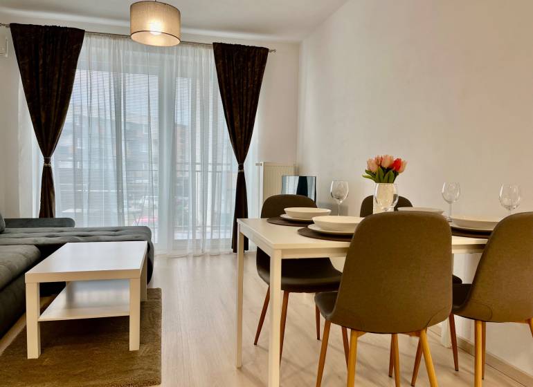 2 szobás lakás fa mintázatú padlóval, étkezőasztallal és kanapéval.