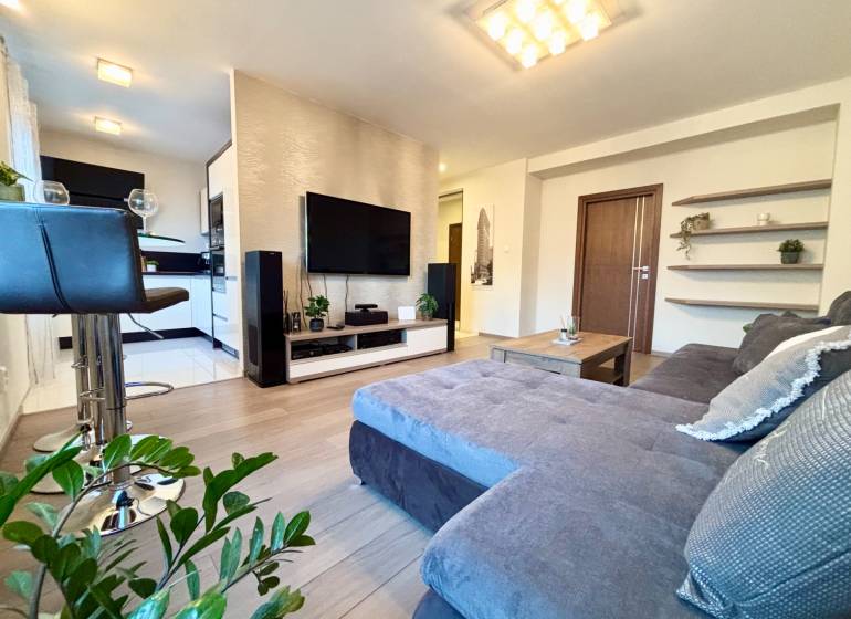 Nappali egy kétszobás lakásban kényelmes kanapéval és fa mintázatú padlóval.