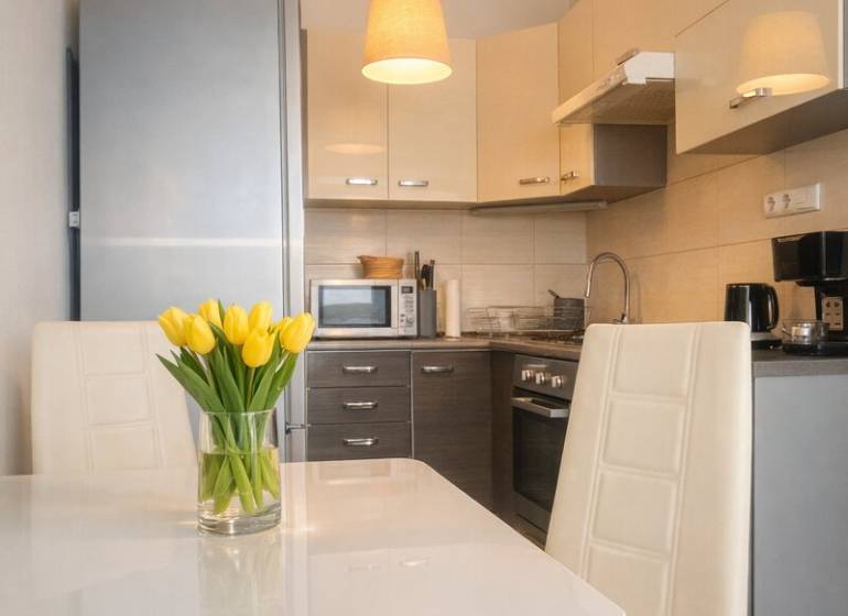 Konyha egy kétszobás lakásban fehér étkezőasztallal és sárga tulipánokkal.