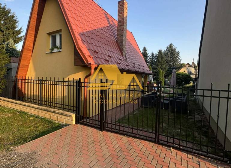 Ház az utcán Érsekújváron, hegyes tetővel és téglakéménnyel.