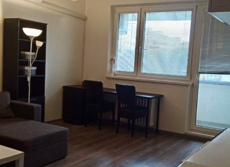 Nappali egy kétszobás lakásban sarokkanapéval és fa dekorációjú padlóval.