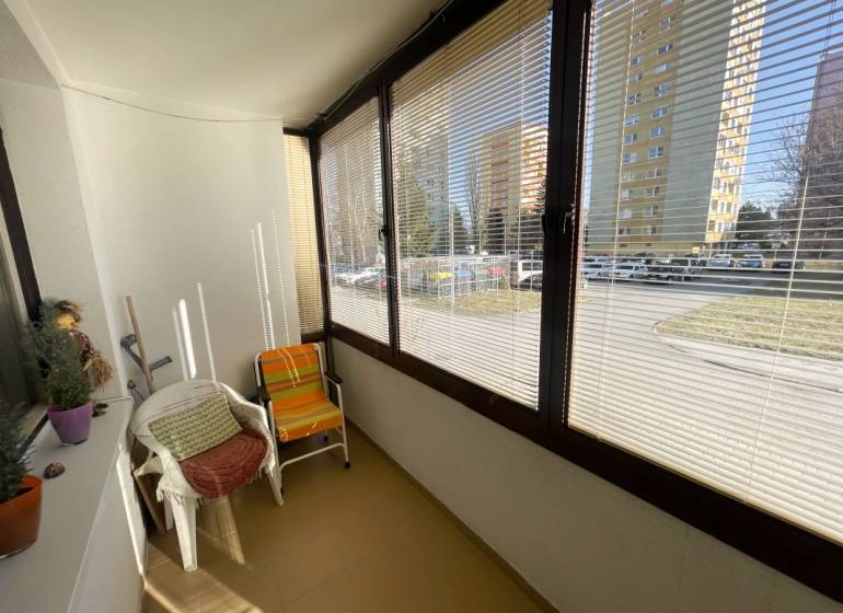 Üvegezett loggia egy 3 szobás lakásban, utcára néző kilátással, székekkel felszerelve.
