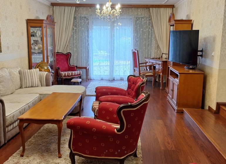 Nappali egy családi házban piros székekkel és fa mintázatú padlóval.