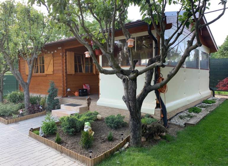 Egy fából készült kerti házikó zölddel körülvéve az alsókrškani kertekben, Nyitrán.