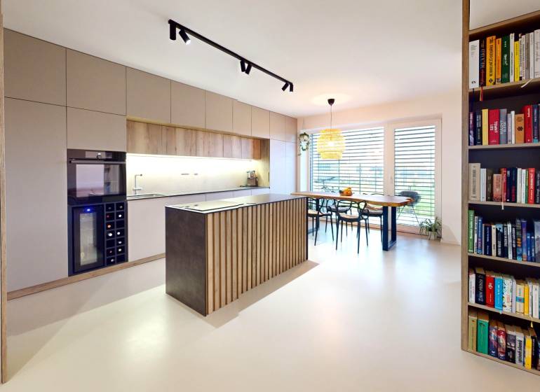 Nyitott konyha étkezőasztallal és könyvespolccal egy családi házban.