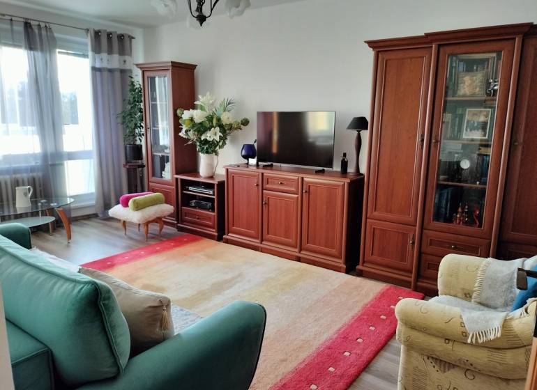 Nappali egy kétszobás lakásban, fa hatású padlóval és kényelmes bútorokkal.