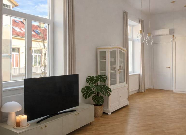 Nappali egy háromszobás lakásban fa dekorációjú padlóval, televízióval és nagy ablakokkal.