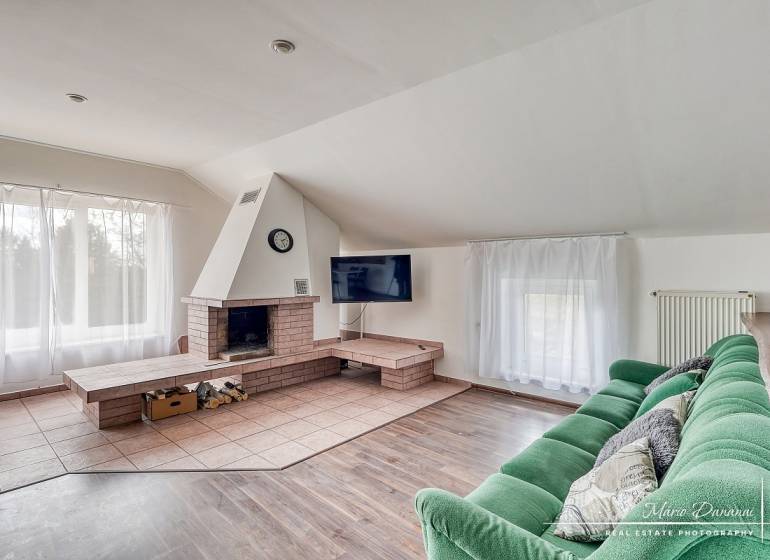 Nappali kandallóval, zöld kanapéval és fa dekorációjú padlóval egy családi házban.