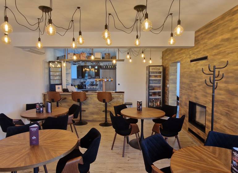 Vendéglátóhelyek fa mintázatú padlóval és függő lámpákkal.