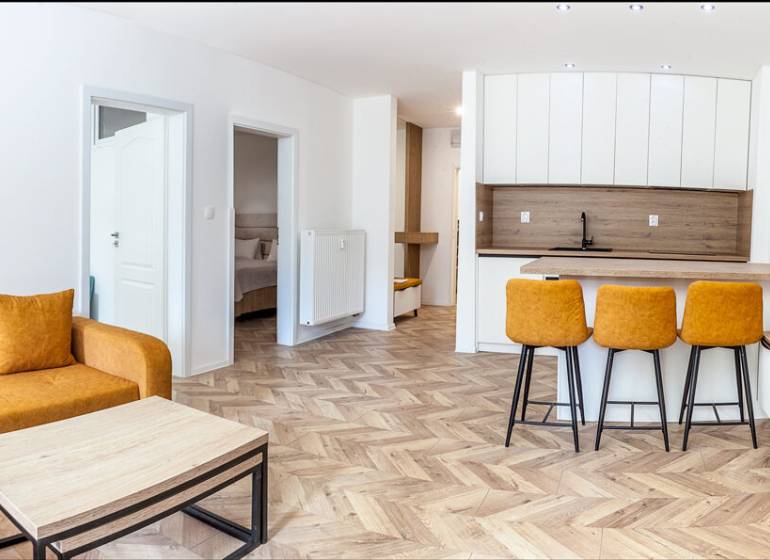 Rekreációs apartman kanapéval, konyhapulttal és fa dekorációjú padlóval.