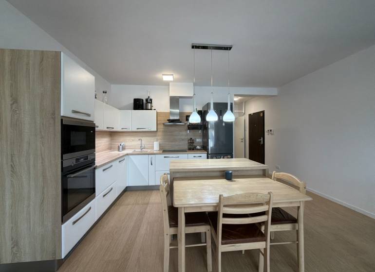 Konyha egy háromszobás lakásban fa dekor padlóval és étkezőasztallal.