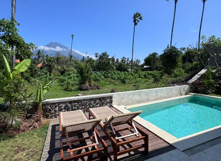 Napozóágyak és napozóágyak kilátással a zöldre az Amed utcában, Amed, egy családi ház mellett.