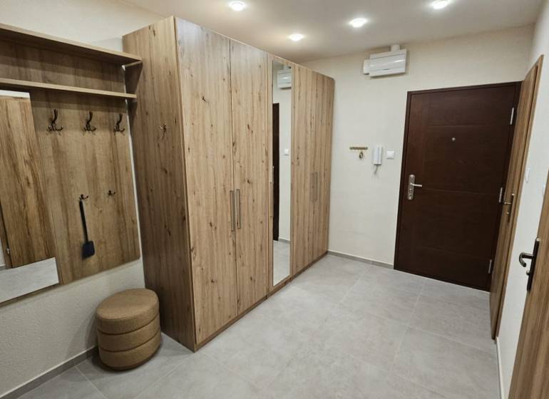 Folyosó egy kétszobás lakásban fa dekorációjú bútorokkal és beépített tükörrel.