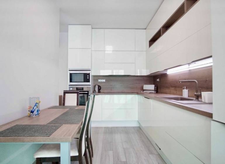 Konyha egy háromszobás lakásban, fa dekorációjú padlóval és világos bútorokkal.