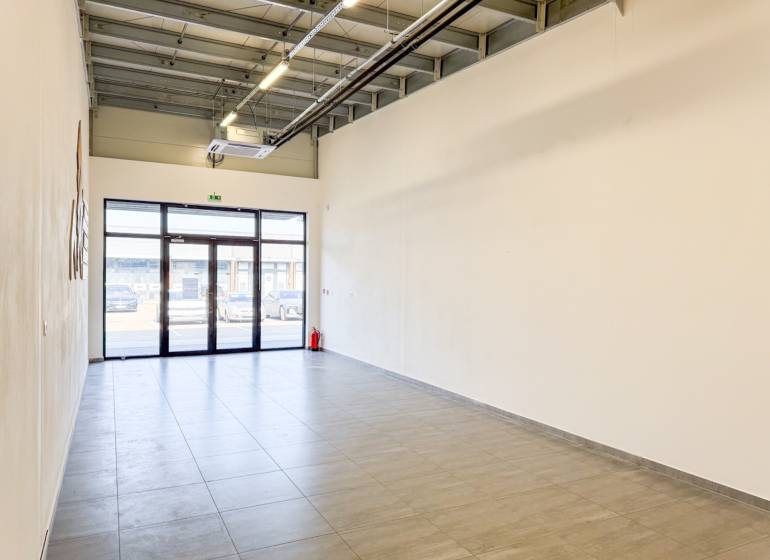 Tágas üzlethelyiségek járólappal és nagy ajtókkal.