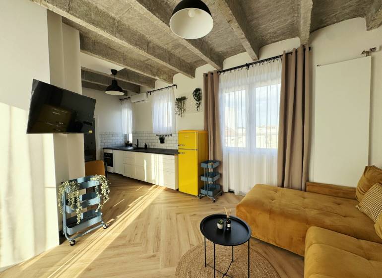 Nappali egy háromszobás lakásban fa dekorációjú padlóval és sárga hűtőszekrénnyel.