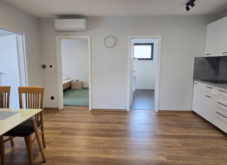 Konyha egy 3 szobás lakásban fa mintázatú padlóval és étkezőasztallal.