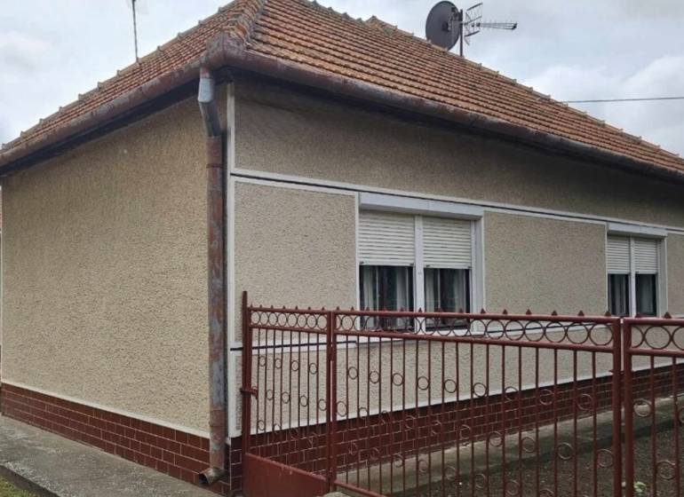 Családi ház Radaván, a Fő utcán, piros tetővel és fehér zsalugáterekkel.