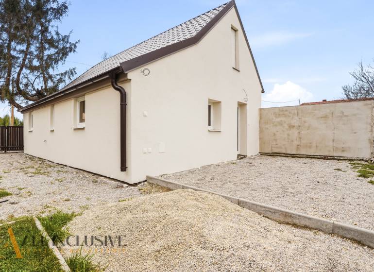 Családi ház Alsóvámoson fehér homlokzattal és ferde tetővel, kavicsos telken.