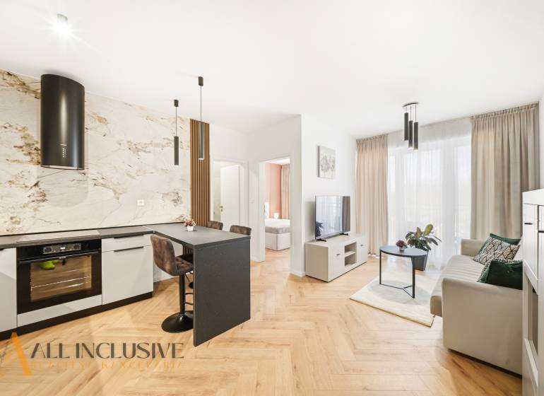 Nappali és konyha egy 4 szobás lakásban, fa dekorációjú padlóval és világos díszítéssel.