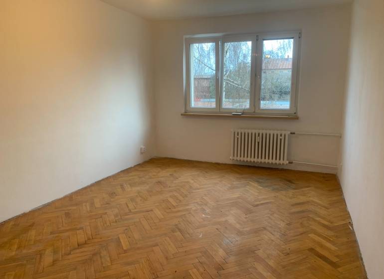 Szoba egy kétszobás lakásban fa dekoros padlóval és nagy ablakkal.