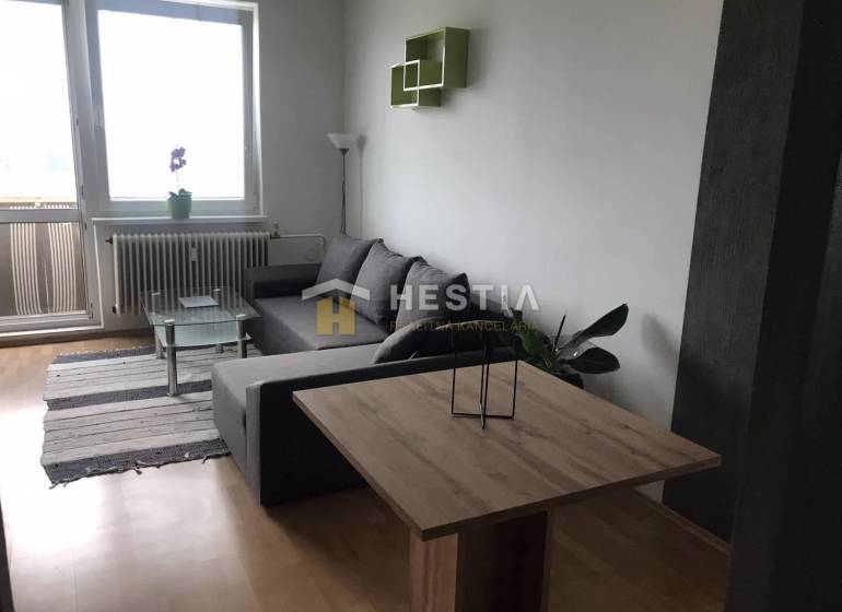 Nappali egy kétszobás lakásban kanapéval és fa dekorációjú padlóval.