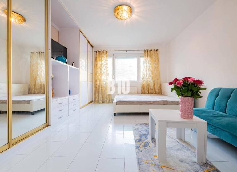 Nappali egy egyszobás lakásban tükörszekrénnyel és fehér padlóval.