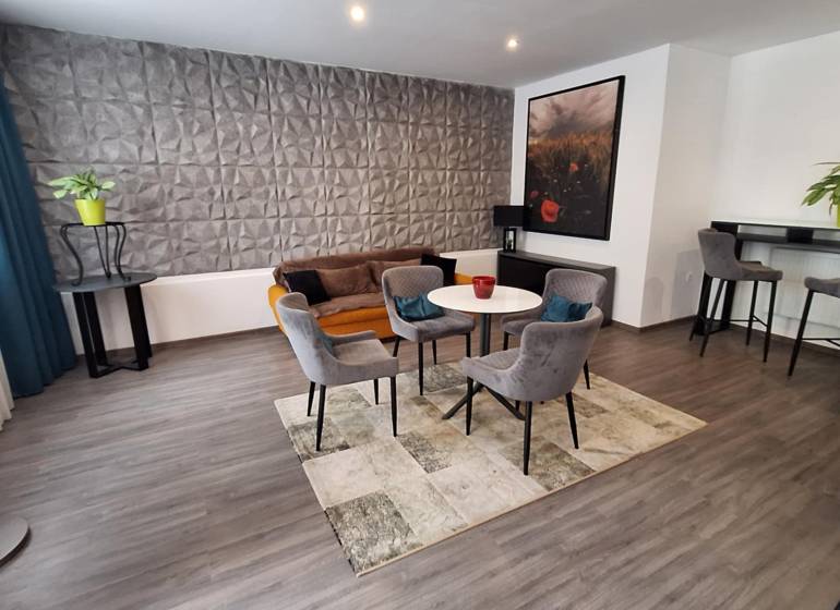 Nappali székekkel és kanapéval egy családi házban, dekoratív fal és bár sarok.