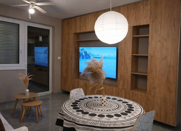 Nappali egy kétszobás lakásban fa dekor padlóval és kerek asztallal.