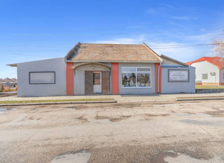 Kereskedelmi helyiségek Okoč városában kirakatokkal és ferde tetővel.