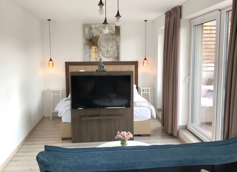 Nappali egy kétszobás lakásban fa dekor padlóval és külön hálószobás zónával.