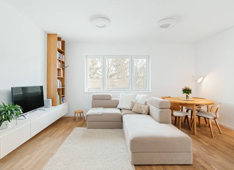 Nappali kanapéval, TV-vel, könyvespolccal és étkezőasztallal, fa dekoros padlóval.