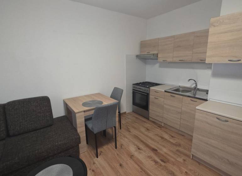 Konyha egy egyszobás lakásban fa dekorációjú padlóval és bútorokkal.