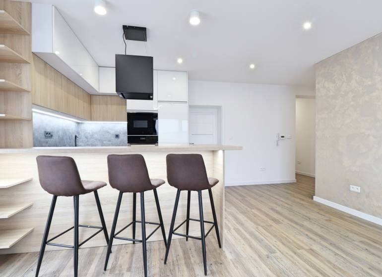 Konyha bárpulttal és fa dekorációjú padlóval egy háromszobás lakásban.
