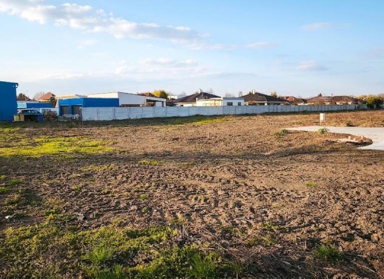 Kereskedelmi területek Vágkirályfán kiterjedt nyílt területtel és bekerített épületekkel.