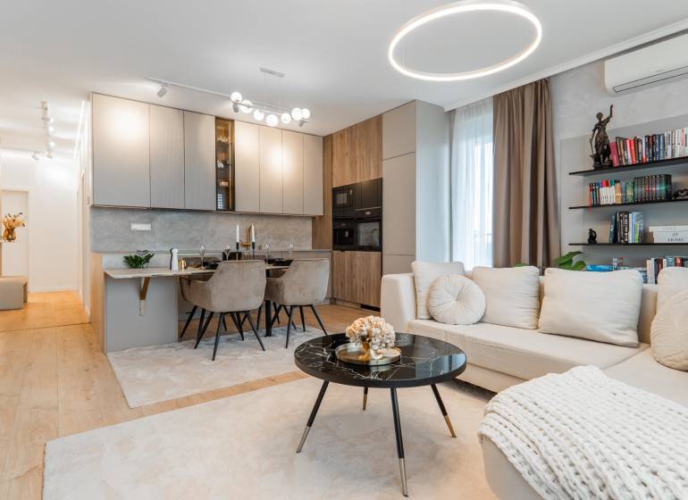 Stílusos nappali konyhával egy 3 szobás lakásban, világos árnyalatok, fa dekoros padló.