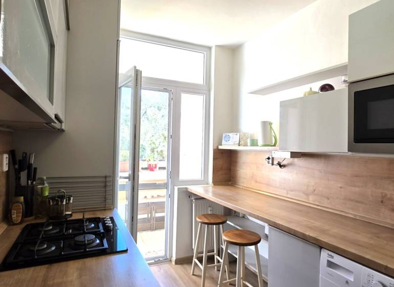 Konyha egy háromszobás lakásban bárpulttal, mikrohullámú sütővel és főzőlappal.