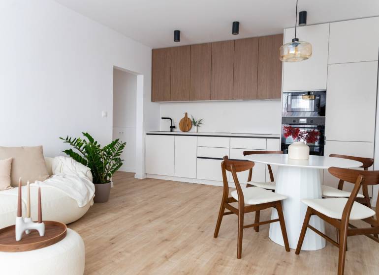 Nappali szoba konyhával egy háromszobás lakásban, fa dekoros padlóval.