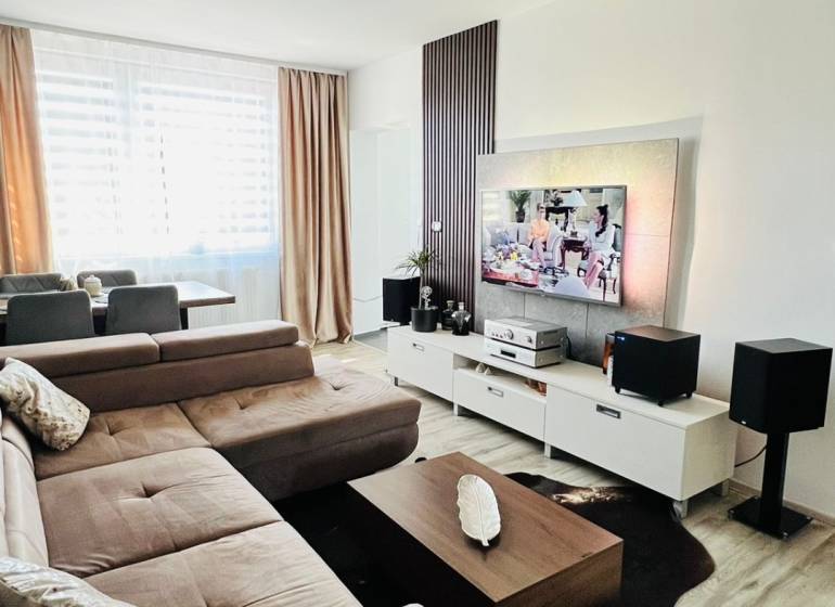 Nappali sarokkanapéval, TV állvánnyal és fa mintázatú padlóval.