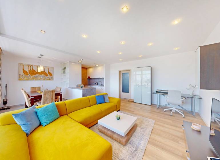 Világos nappali tér élénksárga kanapéval, étkező sarokkal és fa dekorációjú padlóval.