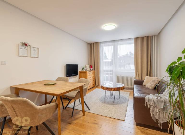 Nappali egy nyaraló apartmanban, hangulatos kanapéval és fa dekorációjú padlóval.