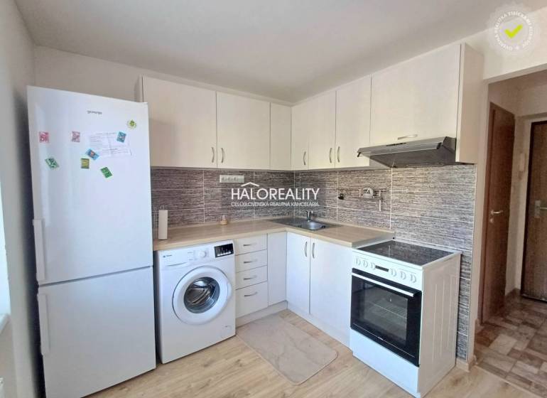 Konyha egy egyszobás lakásban fehér szekrényekkel és fa dekorációjú padlóval.