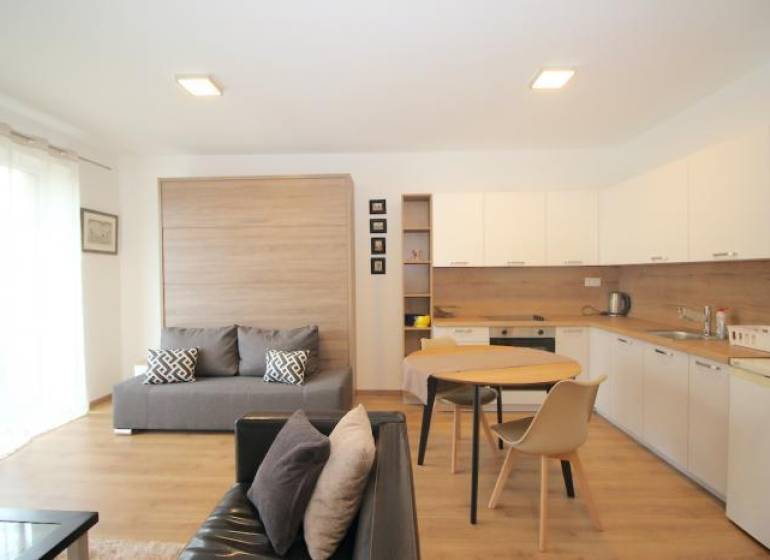 Nappali szoba konyhával egy egyszobás lakásban, fa dekoros padlóval.