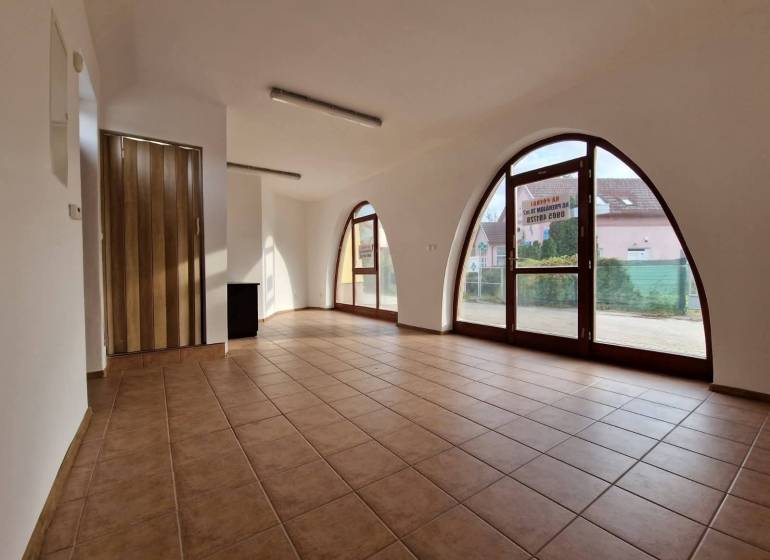 Üzlethelyiségek belső tere nagy boltíves ablakokkal, csempével és faajtókkal.